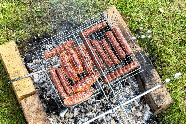 Délicieuses saucisses de viande sur une grille métallique — Photo