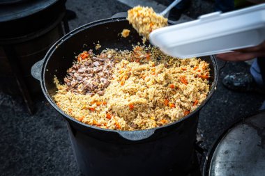 Büyük bir kazanda et ile geleneksel doğu pilavı pişirmek.