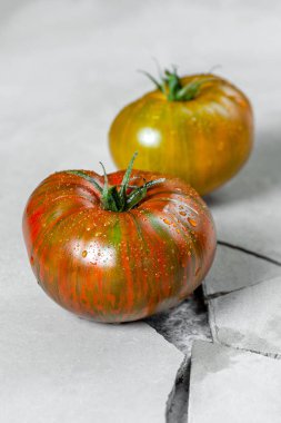 Kalıtsal domates. Bir çatlak bir gri beton masada farklı renkteki iki domates.