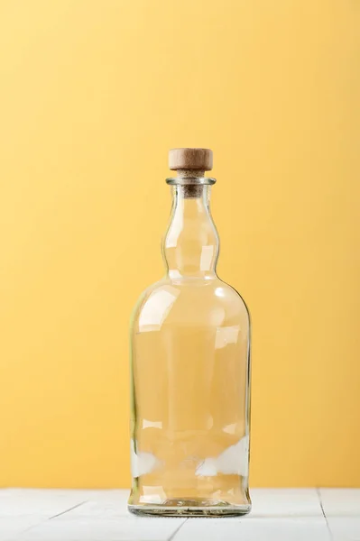 Una botella de vidrio en relieve vacía sobre un fondo blanco-amarillo claro . —  Fotos de Stock