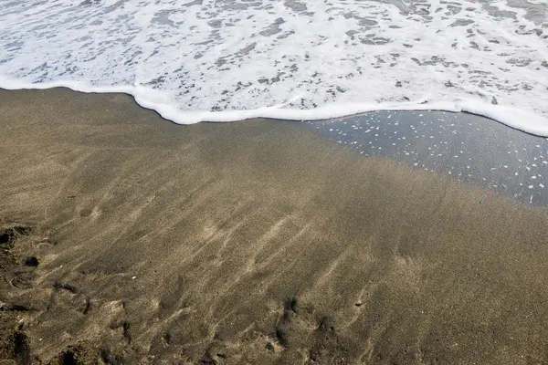 Belle vague douce sur sable noir à la mer — Photo