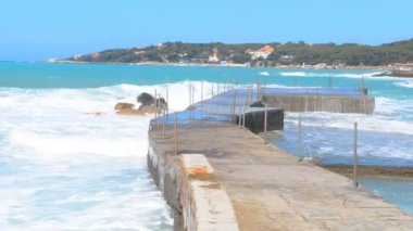 Denizde fırtına. Büyük dalgalar. İskeleden manzara. Mavi gökyüzü ve deniz.