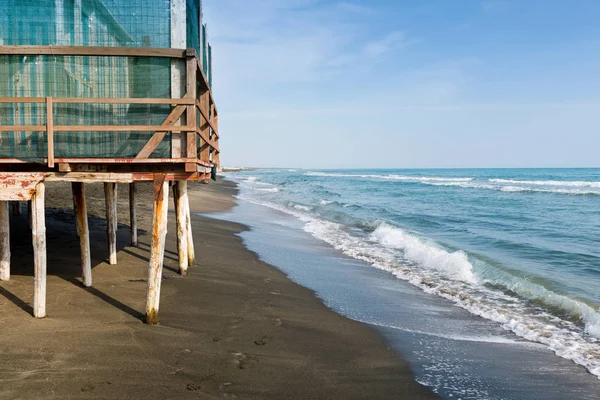 Mar bonito, a praia de areia preta e branco e azul listrado casas de praia — Fotografia de Stock