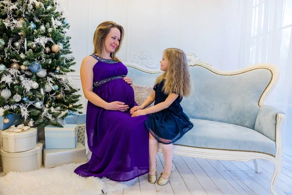 Hermosa mujer embarazada en vestido ultra violeta sentado con doughter —  Fotos de Stock