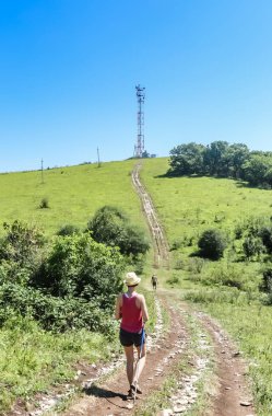 Turistler bir tepenin üstünde iletişim kule yol boyunca yürümek