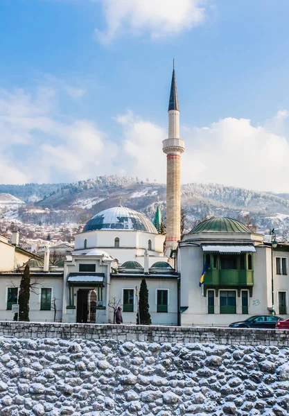 Ein Minarett erhebt sich über Gebäuden auf der anderen Flussseite des Altstadtviertels von Sarajevo, Bosnien-Herzegowina — Stockfoto