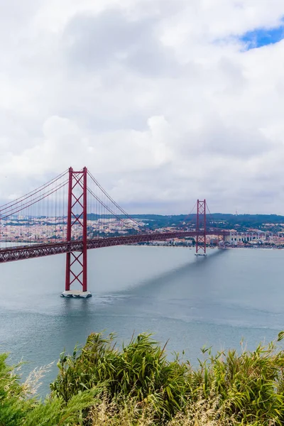 Γέφυρα Πόντε 25 de Abril στη Λισαβόνα, Πορτογαλία. Συνδέει τις πόλεις της Λισαβόνας και της Αλμάδα διασχίζοντας τον ποταμό Τάγο. Θέα από την Αλμάδα με τη Λισαβόνα σε όλη — Φωτογραφία Αρχείου
