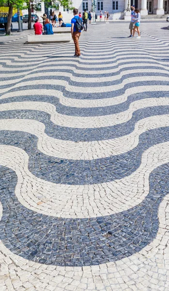Toeristen lopen op geplaveide stoep met golvend patroon, Lis — Stockfoto