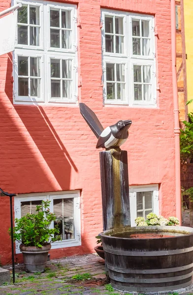 Sculpture of  magpie sits in a garden outside timber framed hous — Stock Photo, Image