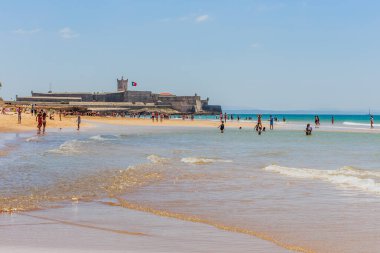 Güneşli bir sonbahar gününde arka planda Sao Juliao da Barra Kalesi ile Carcavelos Plajı
