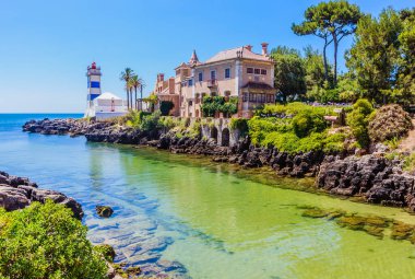Portekiz, Cascais 'deki Santa Marta Deniz Feneri' nin yanındaki kayalık sahil şeridi boyunca uzanan körfezin muhteşem manzarası. 