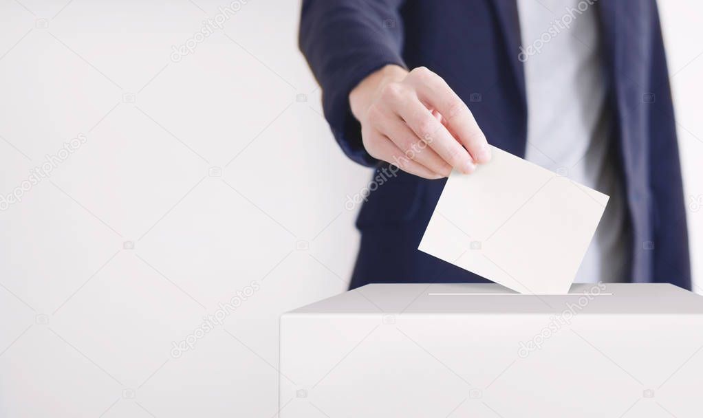 Voting. Man putting a ballot into a voting box.