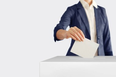 Voting. Woman putting a ballot into a voting box. clipart