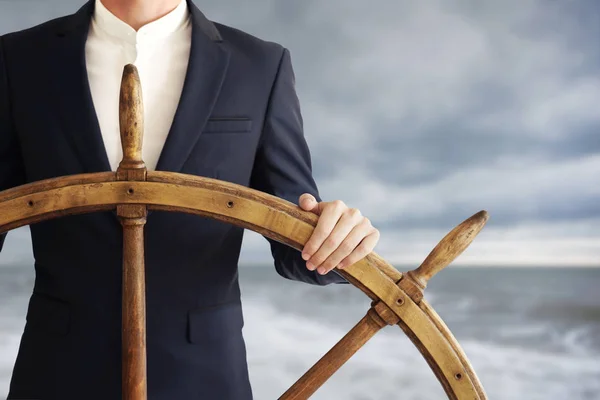 Empresário segurando roda do navio e navega na tempestade . — Fotografia de Stock