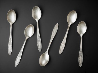 old silver spoons on black background clipart