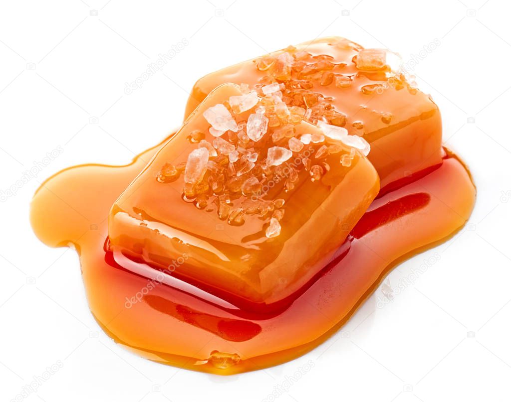 two pieces of melted caramel candies with sauce and salt isolated on white background