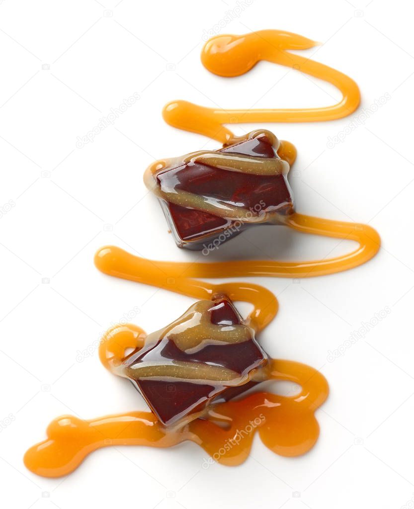 chocolate candies and caramel sauce isolated on white background, top view