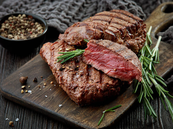 Grilled beef fillet steak meat on dark wooden table