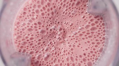 Çilekli ve muzlu, pembe milkshake karışımı. Üst Manzara. Ağır çekim. Sağlıklı protein smoothie içecek konsepti, yiyecek yakın çekim