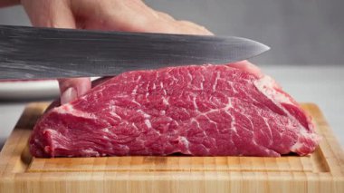 Şef, et kesmek için tahtayı bıçakla kesti. Sağlıklı yemek ve yemek yapmak için, şef çiğ eti parçalara ayırdı, biftek için dilimledi. Biftek fileto, yakın plan yemek.