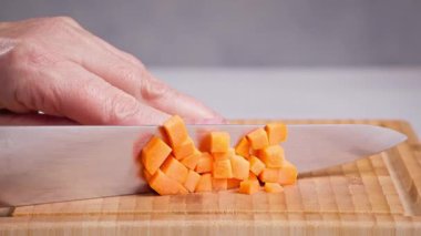 Şef, sağlıklı yemek ve yemek yapmak, havuç kesmek, salata yapmak, mutfakta yemek yapmak için havuç kesmek için keskin bıçakla tahtayı kesti.