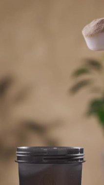 Protein tozu, ölçü kaşığından kabın içine dökülür. beyaz spor beslenmesi. Spor ya da diyet içeceği hazırlamak için kuru karışım.