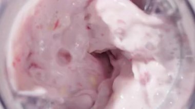 Sağlıklı kahvaltı içeceği, üst manzara, yavaş çekim için blender 'a çilek ve muz parçaları karıştırılmış taze süt.