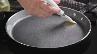 Yağ fırçayla kızgın tavaya uygulanır. Mutfakta ev yapımı krep yapmak için pişirme işlemine yakın çekim