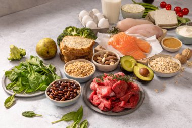 Gri arka planda çeşitli taze protein diyet ürünlerinin bileşimi. Sağlıklı beslenme, gri masa üstünde çeşitli sağlıklı ürünler. Sağlıklı yiyecekler temiz yemek seçimi