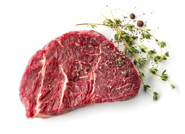 Beyaz arka planda izole edilmiş kekik ve biberli taze çiğ biftek dilimi.