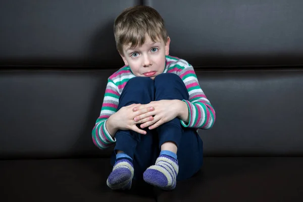 Niño Seis Años Con Una Mueca Sorpresa Sienta Sofá — Foto de Stock