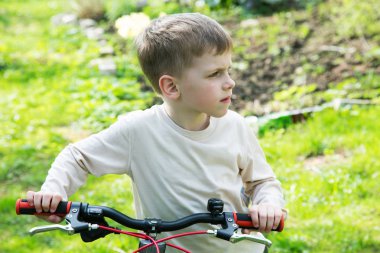 küçük çocuk bir bisiklet ile bir bahar gününde duruyor