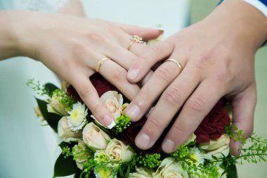 düğün buketi üzerinde alyans ile gelin ve damat elleri