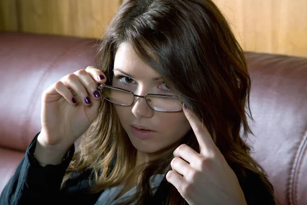 Το κορίτσι με τα γυαλιά και ένα σακάκι για το close-up καναπέ — Φωτογραφία Αρχείου