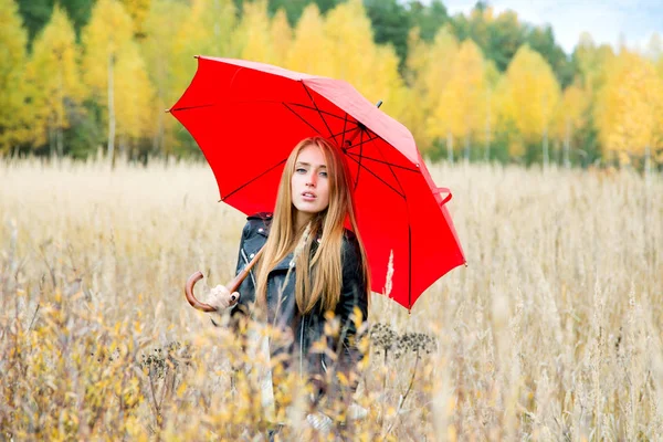 Dziewczyna z czerwonym parasolem w polu na jesienny popołudnie na — Zdjęcie stockowe