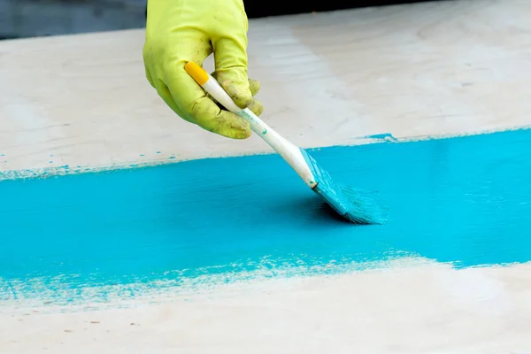 Brush with turquoise paint close-up on a painted surface backgro — Stock Photo, Image