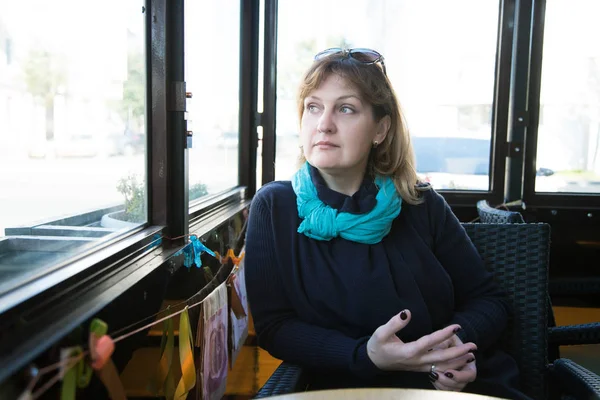 Pensive woman sitting in a cafe and twists the ring on her finge — Stock Photo, Image