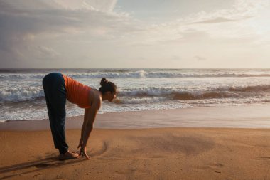 Kadının Yoga Sun salutation Surya Namaskar plajda yapması