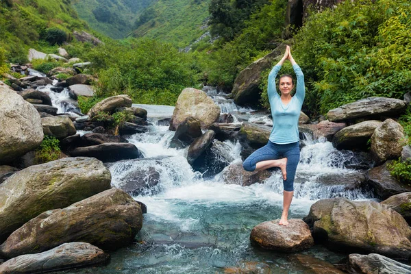 Женщина в йоге Асана Vrikshasana дерево позировать у водопада на открытом воздухе — стоковое фото