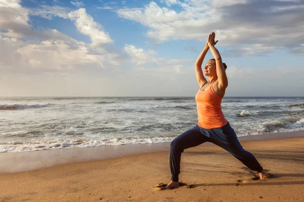 Mulher fazendo ioga asana Virabhadrasana 1 guerreiro dose na praia em — Fotografia de Stock