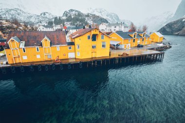 Nusfjord 'un otantik balıkçı köyünün panoramasında kışın Norveç fiyortlarında sarı rorbu evleri bulunur. Lofoten Adaları, Norveç