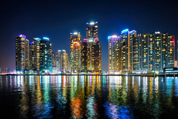 Busan Marina city skyscrapers illluminated in night with reflection in water, South Korea