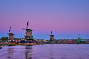 Hollanda Zaanse Schans 'daki yel değirmenleri gün batımında alacakaranlıkta. Zaa