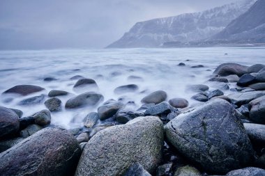 Waves of Norwegian sea surging on stone rocks. Long exposure clipart