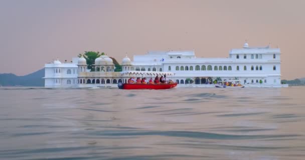 Озеро Удайпур Дворец Джаг Нивас на острове на озере Пичола с туристическими лодками - раджпутская архитектура правителей Раджастхана династии Мевар. Закат в Удайпуре, Индия — стоковое видео
