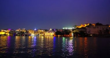 Gün batımında güzel Pichola Gölü kıyısındaki Udaipur Şehir Sarayı Rajput mimarisi Rajasthan 'ın Mewar Hanedanı hükümdarları. Su dalgaları şehir manzarasını yansıtır. Udaipur, Hindistan. Yatay tava