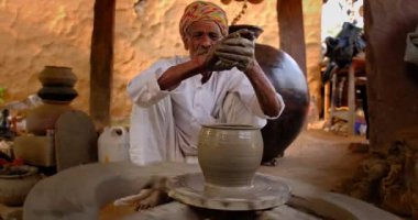 Hintli çömlekçi: çömlekçi çarkını fırlatmak ve seramik kap ve kil kapları şekillendirmek: çömlek atölyesinde kap, kavanoz. Tecrübeli usta. Shilpagram, Udaipur, Rajasthan, Hindistan 'dan el işi.