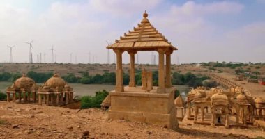 Hint Thar Çölü 'nde kumtaşından yapılmış Bada bagh cenotaphs (Hindu mozolesi). Arka planda rüzgar jeneratörü var. Jaisalmer, Rajasthan, Hindistan. Yatay kaydırma