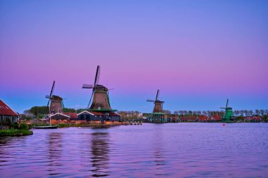 Hollanda Zaanse Schans 'daki yel değirmenleri gün batımında alacakaranlıkta. Zaa