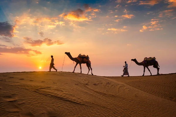 Indiase kamelenrijder met kameel silhouetten in duinen bij zonsondergang. Jaisalmer, Rajasthan, India — Stockfoto